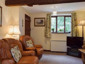 a living room with a leather chair and a television at The Shippon in Burscough