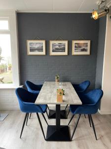 une salle à manger avec une table et des chaises bleues dans l'établissement DuinHotel Texel, à De Koog