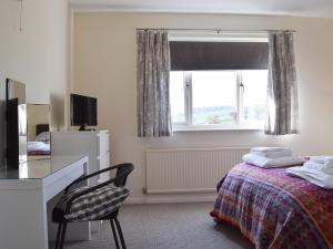 1 dormitorio con cama, escritorio y ventana en Roundhill, en Eydon
