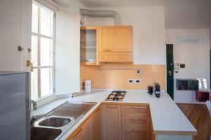 una cucina con armadi in legno, lavandino e finestra di Torretta10 - Studio Apartment a Trieste