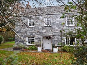 une maison en briques grises avec une porte blanche dans l'établissement Maidenland, à Saint Kew