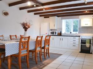 Bestdale في Frosterley: مطبخ مع طاولة وكراسي ومطبخ مع دواليب بيضاء