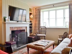 a living room with a fireplace and a tv at Marsh Barn in Brancaster