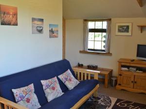 uma sala de estar com um sofá azul e uma televisão em Horseshoe Cottage -31299 em Holywell Bay
