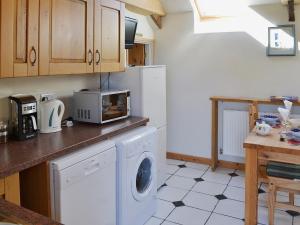 uma cozinha com máquina de lavar e secar roupa em Horseshoe Cottage -31299 em Holywell Bay