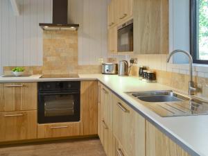 a kitchen with wooden cabinets and a sink at Blackberry Lodge in Cheddar