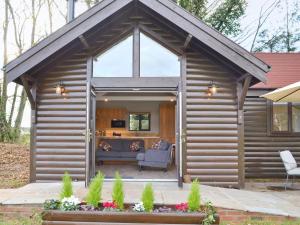 a log cabin with a large window and a chair at Blackberry Lodge in Cheddar