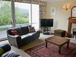 a living room with a couch and a table and a tv at Waterside in Bowness-on-Windermere