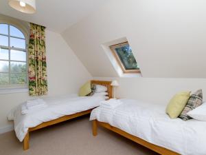 two twin beds in a room with a window at One The Stables in Dalrymple