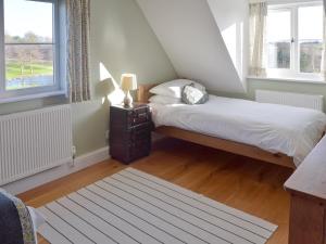 um pequeno quarto com uma cama e uma janela em Granary Cottage em Bentley
