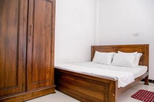 1 dormitorio con 1 cama y armario de madera en Villa 146 Dickwella, en Batigama