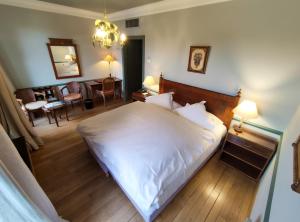 - une chambre avec un lit blanc et un salon dans l'établissement Le Manoir Au Lac, à Gérardmer