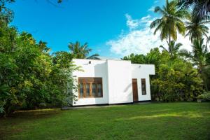 una casa blanca en un patio con palmeras en Villa 146 Dickwella, en Batigama