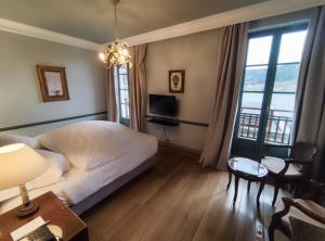 a bedroom with a bed and a desk and a television at Le Manoir Au Lac in Gérardmer