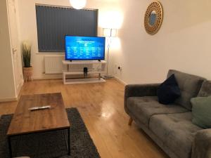 a living room with a couch and a flat screen tv at Montrose House - Spacious Comfy 3 Bedroom House, Free Wifi and Free Parking in Swindon