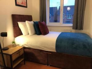 uma cama com almofadas e uma janela num quarto em Montrose House - Spacious Comfy 3 Bedroom House, Free Wifi and Free Parking em Swindon