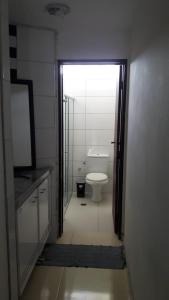 a bathroom with a toilet and a door leading into a room at Casa de praia da maria Luiza in Barra de São Miguel