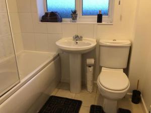 a white bathroom with a toilet and a sink at Montrose House - Spacious Comfy 3 Bedroom House, Free Wifi and Free Parking in Swindon