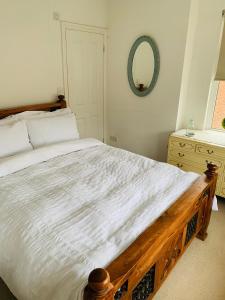 a bedroom with a bed with a wooden frame and a mirror at Elegant 3BD Edwardian Home Warminster in Warminster