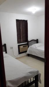 1 dormitorio con 2 camas y ventana con ventilador en Casa de praia da maria Luiza, en Barra de São Miguel