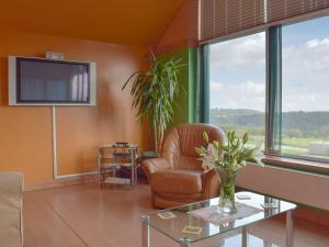 a living room with a leather chair and a tv at Elm Cottage-w40630 in Gelliwen