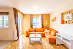 a living room with an orange couch and a table at Karchna Erica central location in countyside with large barbecue area in Novalja
