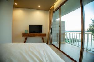 1 dormitorio con cama, TV y balcón en LAKE HOUSE Naka Cave, en Ban Don Klang