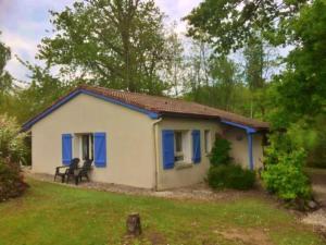 una piccola casa bianca con persiane blu in un cortile di Vakantie Woning Le Chat Maison 175 a Écuras