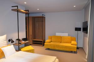 a bedroom with a bed and a yellow couch at Boutique Hotel Moselgarten in Bullay