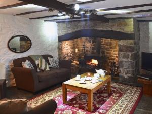 a living room with a couch and a table with a fireplace at Bwthyn Barri in Sarnau