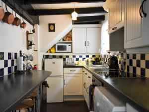 une cuisine avec des placards blancs et un comptoir noir dans l'établissement White Cottage, à Whitby