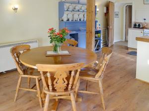 une table en bois avec des chaises et un vase de fleurs. dans l'établissement Bats Cottage, à Tipton Saint John
