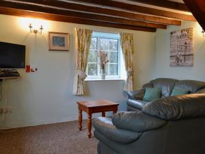 a living room with a leather couch and a table at Commonwealth Cottage in Iron Acton