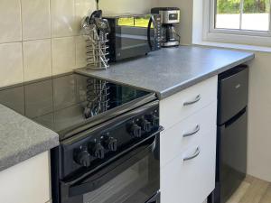 a kitchen with a black stove and a microwave at Commonwealth Cottage in Iron Acton