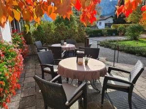 een patio met 2 tafels, stoelen en bloemen bij Hotel Filser in Füssen