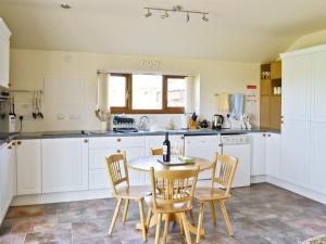 KelsallにあるWeetwood Lodgeの白いキャビネット、テーブルと椅子付きのキッチンが備わります。