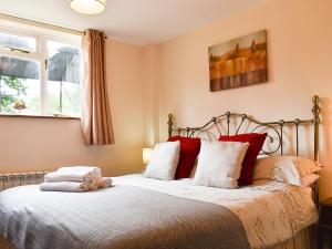 sypialnia z łóżkiem z białymi i czerwonymi poduszkami w obiekcie Barn Terrace - 28972 w mieście Selstead