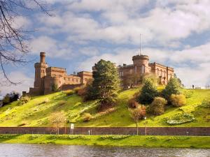 a castle on top of a hill next to a body of water at Forest Lodge in Kirkhill