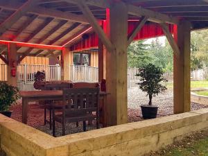 a wooden pergola with a wooden table and a bench at Forest Lodge in Kirkhill