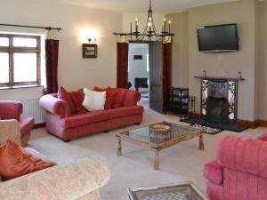 a living room with red furniture and a fireplace at Trescowthick Barn in Zelah