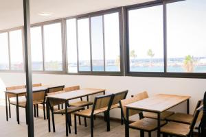 a row of tables and chairs in a room with windows at Ocean Nomads Coworking in Arona