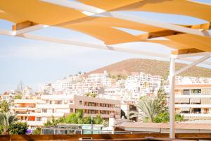 a view of a city from under a yellow umbrella at Ocean Nomads Coworking in Arona