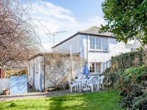 a white house with a table and chairs in the yard at Bowjy Cottage in Cubert