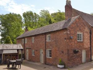 an old red brick building with a table and chairs at Burdettes Cottage - 25349 in Findern