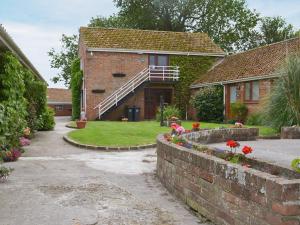 a house with a brick wall and flowers in the yard at Pine Cottage in Cote