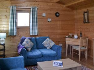 a living room with a blue couch and a table at Birdsong Cabin in Breakish