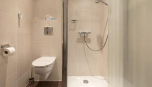a white bathroom with a shower and a toilet at Onder de molen in Hollum