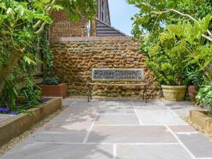 a garden with a bench in front of a brick wall at The Mistress House in Hunstanton