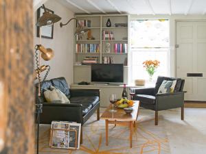 a living room with two black couches and a television at Smugglers Cottage in Margate