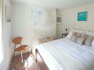 a bedroom with a white bed and a chair at Smugglers Cottage in Margate